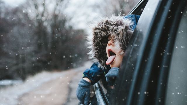 Boy looking out of car window in the snow